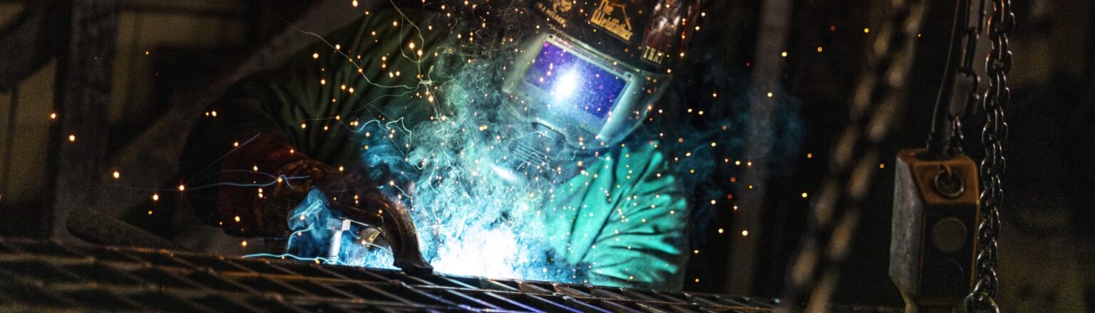 Worker welding grate in manufacturing facility