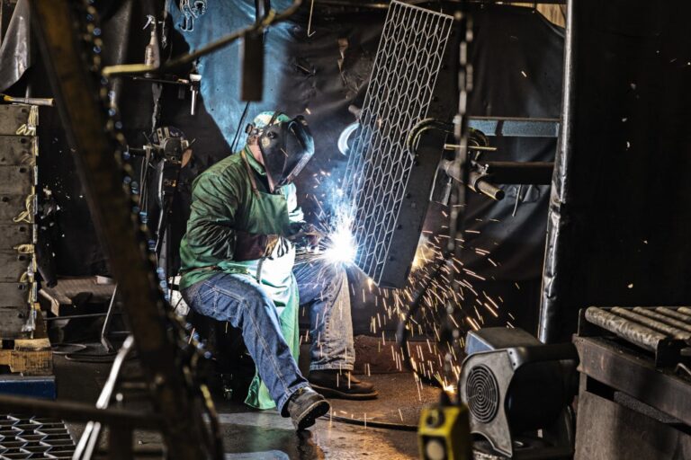 Worker welding grate at manufacturing facility